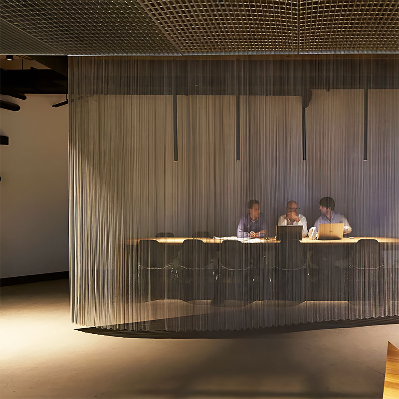 Decorion QKRMC decorative stainless steel ring mesh curtain used as a modern room divider in a commercial interior setting.
